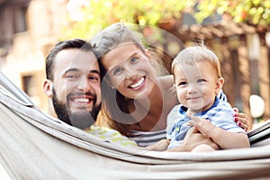 Happy parents playing with their baby boy in hammock