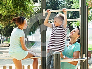 Happy parents with son training on pull-up bar