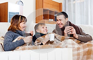 Happy parents and son warming near warm heater
