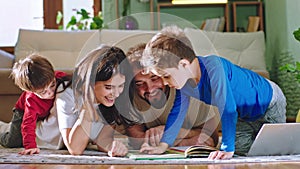 Happy parents spending good time together while sitting down on the floor they reading a story book smiling large