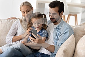 Happy parents and sweet gen Z kid using smartphone