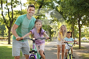 Happy parents teaching their children to ride bicycle in