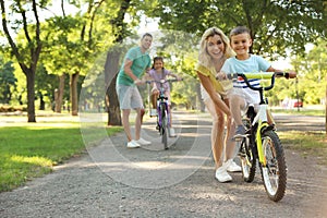 Happy parents teaching their children to ride bicycle in