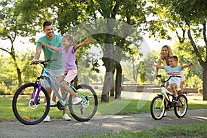 Happy parents teaching their children to ride bicycle