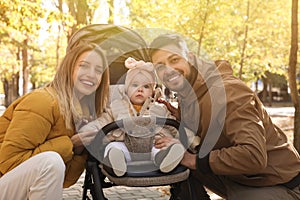 Happy parents with their baby in stroller at park on sunny day