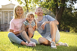 Happy parents with their child having fun on green grass. Spending time in nature