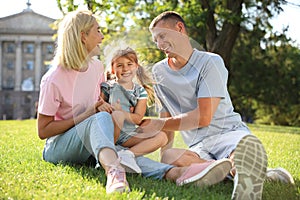 Happy parents with their child having fun on green grass. Spending time in nature