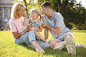 Happy parents with their child having fun on green grass. Spending time in nature