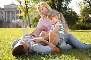 Happy parents with their child having fun on green grass. Spending time in nature