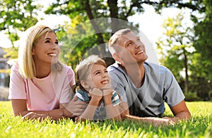 Happy parents with their child having fun on green grass. Spending time in nature