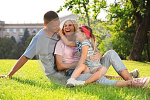 Happy parents with their child having fun on green grass. Spending time in nature