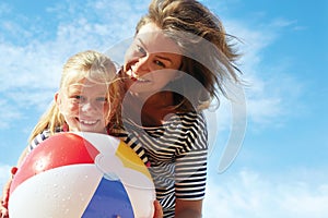 Happy parents and their child playing with a ball at the beach