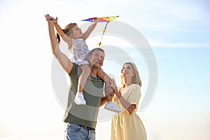 Happy parents with their child playing with kite on beach. Spending time in nature