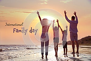 Happy parents and their children on sandy beach near sea at sunset, back view. Happy Family Day