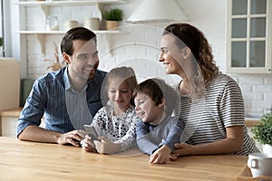 Happy parents using cellphone with small kids.