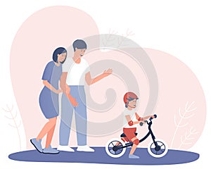 Happy parents watch how a child learns to ride a balance bike