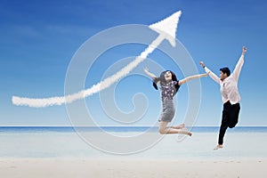 Happy partners jump under increase arrow sign cloud at beach