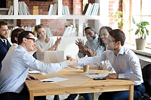 Happy partners shake hands get team applause after successful negotiations