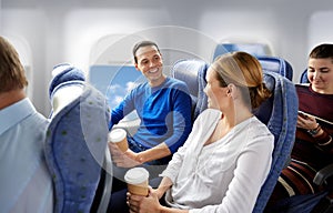 Happy passengers with coffee talking in plane