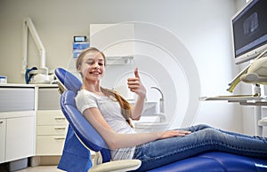 Happy patient girl showing thumbs up at clinic