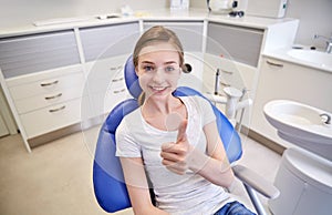 Happy patient girl showing thumbs up at clinic