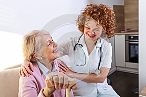 Happy patient is holding caregiver for a hand while spending time together. Elderly woman in nursing home and nurse. Aged elegant