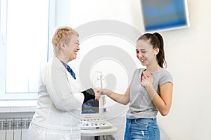 Happy patient shakes hands with doctor after successful ultrasound examination. In the white office of a medical clinic