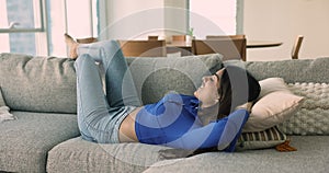 Happy peaceful young 20s Indian woman lying on couch