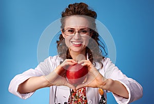Happy pediatrist doctor showing an apple on blue photo