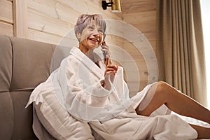 Happy pensioner communicates on her mobile phone in the bedroom