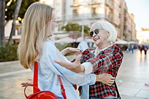 Happy pensioner female and young woman greeting each other outdoors