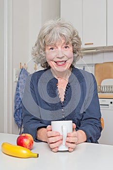 Happy pensioner at kitchen table