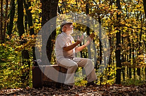 Happy pensioner relax on autumn nature. Retirement travel and hobbies. Ecology. Mature man hold yellow leaves