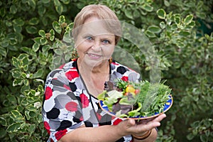 Happy pensioner woman with vegetables at dacha