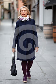 Happy pensioner woman walks the streets of a tourist city