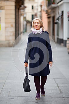 Happy pensioner woman walks the streets of a tourist city