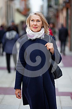 Happy pensioner woman walks the streets of a tourist city