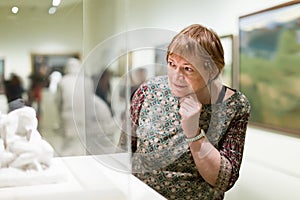 Happy pensioner woman watching at sculpture