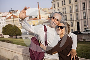 Happy Pensioners Couple With Backpack Making Selfie Using Smartphone Outdoor