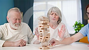 happy pensioners playing board games together with a female social worker while sitting at table