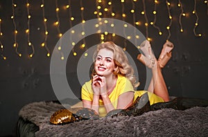 Happy pensive young woman on sofa festive lights background