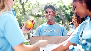 Happy people, box and food with donations for charity, NGO or community together in nature. Group of volunteers with