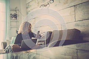 Happy people caucasian blonde curly woman at home with technology internet devices - enjoying computer laptop and cellular phone