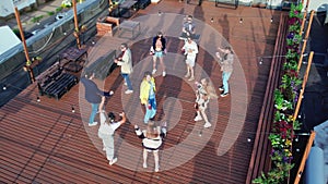 Happy people dancing roof party summer outdoor discotheque at sunset terrace aerial panning view