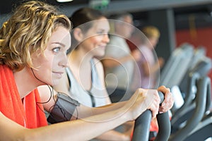 Happy people doing indoor biking in fitness club