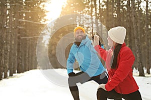 Happy people doing sports exercises in winter forest