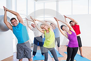 Happy people doing stretching exercise in yoga class