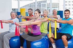 Happy people exercising with resistance bands in gym