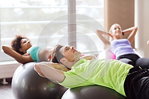 Happy people flexing abdominal muscles on fitball