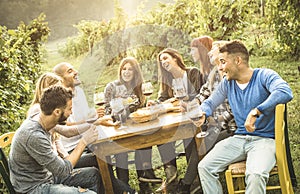 Happy people friends having fun outdoor drinking red wine at vineyard
